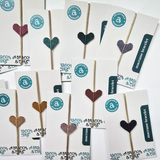 A collection of heart-shaped macrame bracelets in various colors, displayed on cards with the brand name 'A Branch & Cord'.