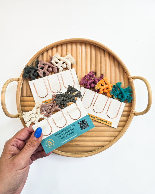 Hand holding a box of hair ties with a tray of colorful hair ties on a white background