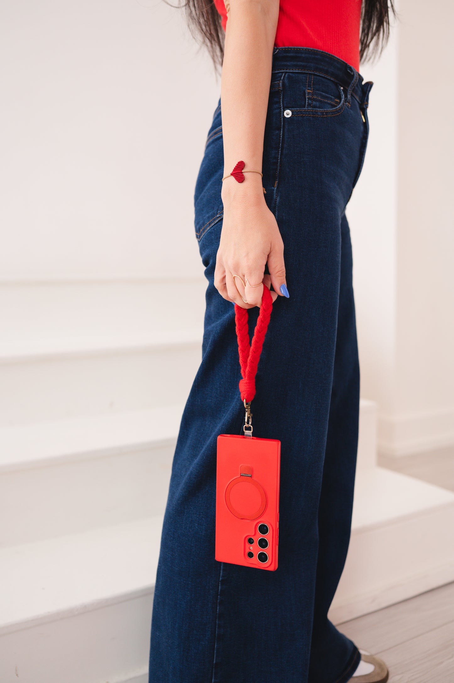 Person holding a red phone case with a strap against a white background