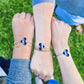 Three arms with blue heart-shaped bands on wrists against a grassy background