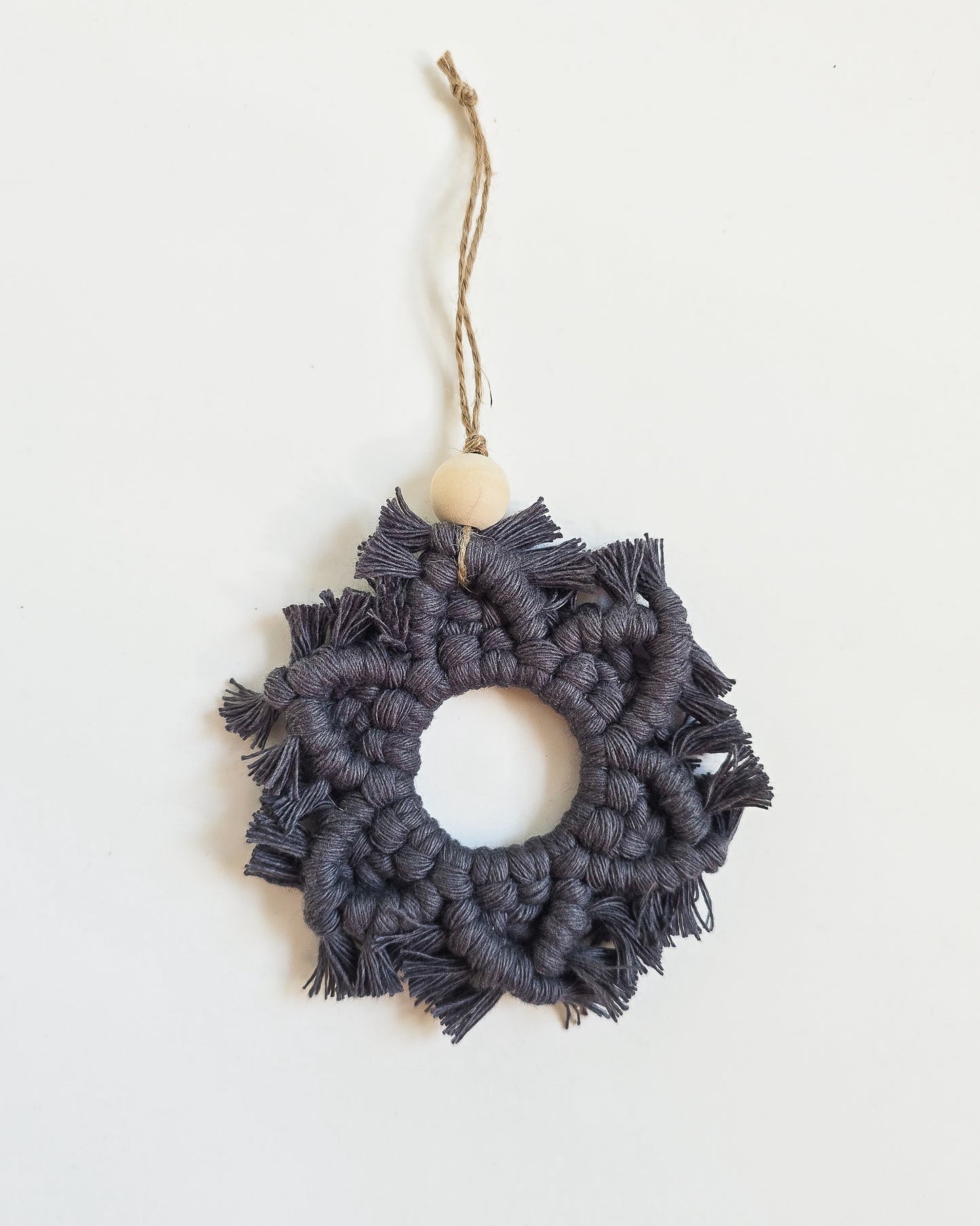 A charcoal colored macrame snowflake ornaments on a white background