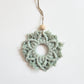 A light agave colored macrame snowflake ornaments on a white background