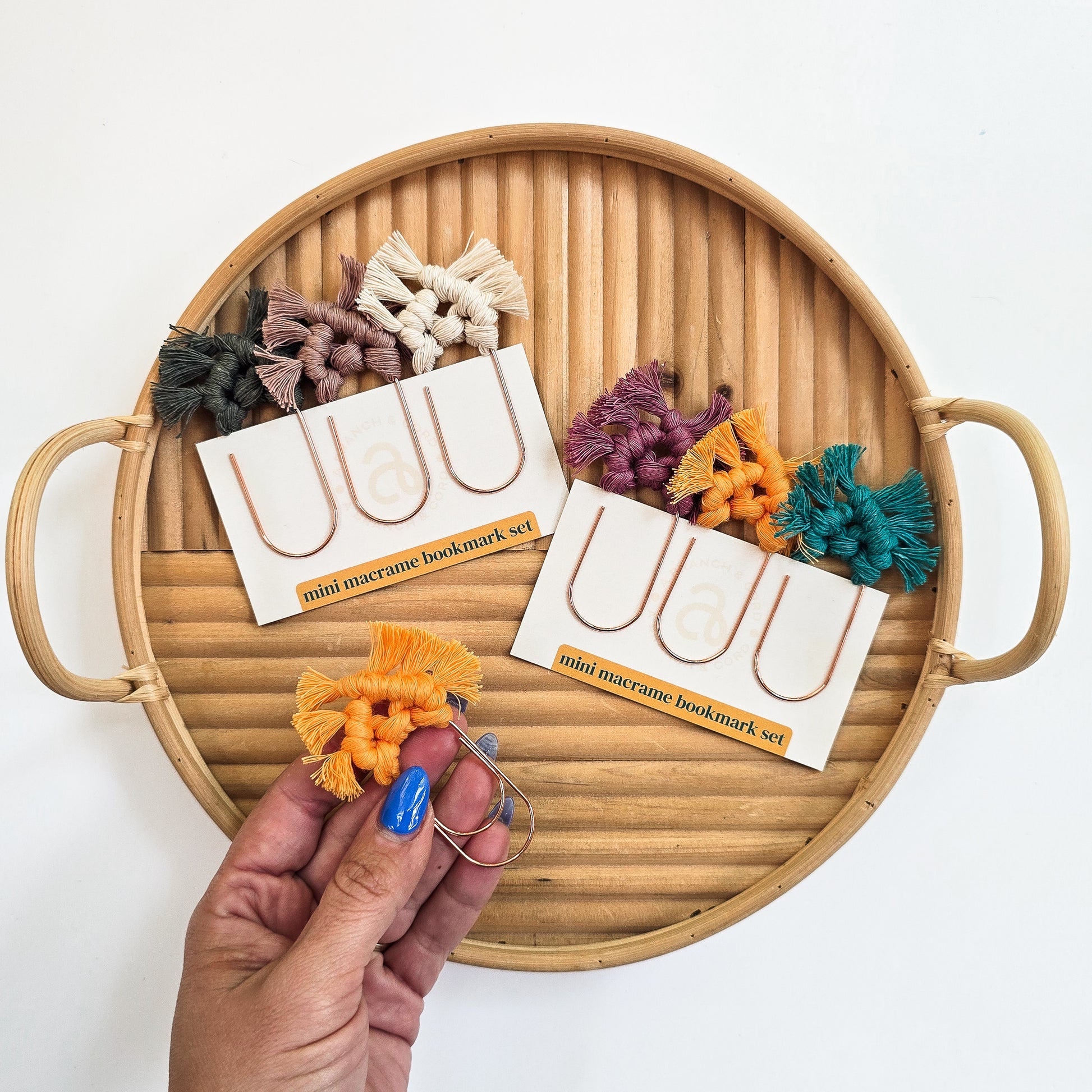 Mini macrame bookmark set with colorful bookmarks on a wooden tray.