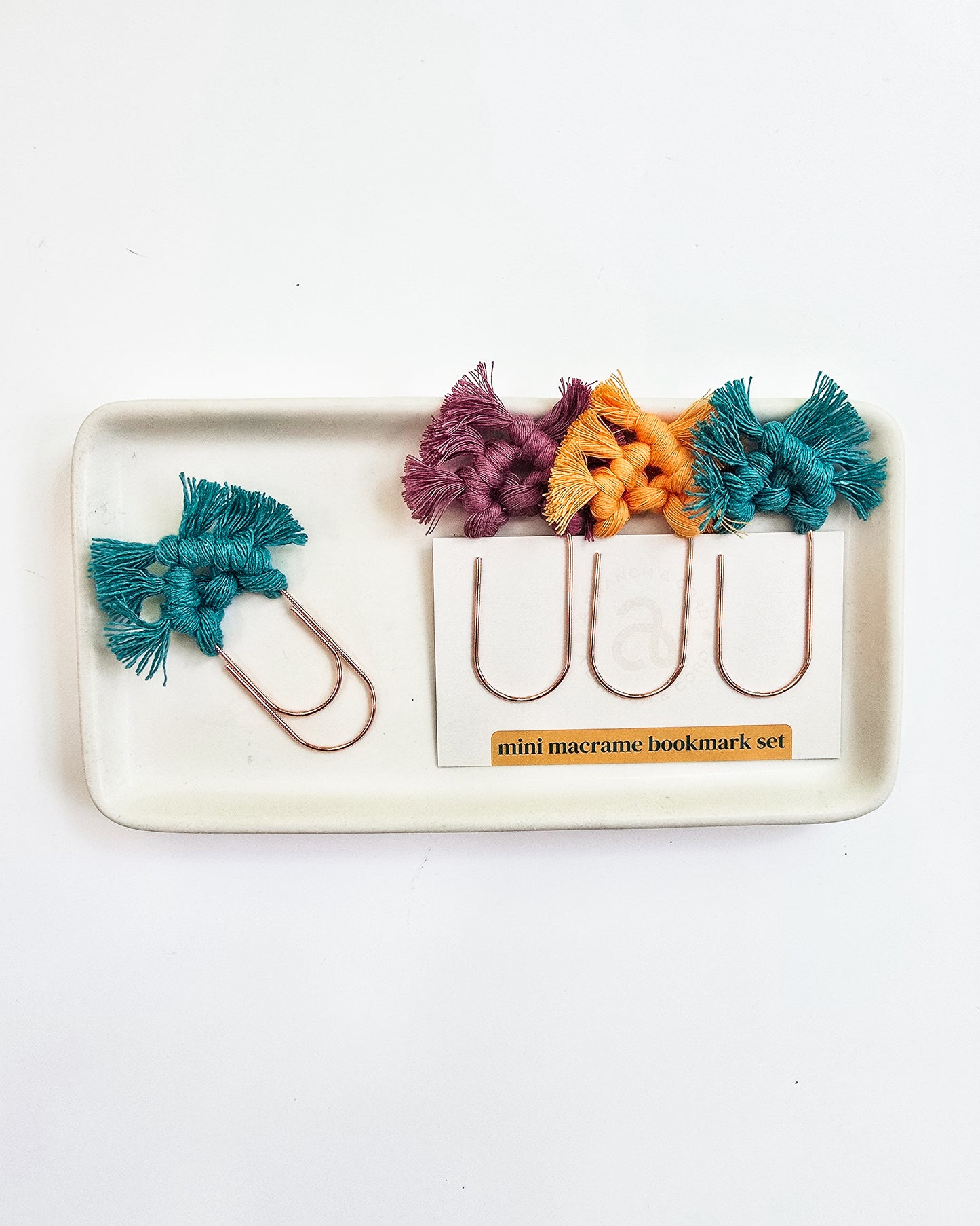 Set of colorful macrame bookmarks on a white tray with a white background