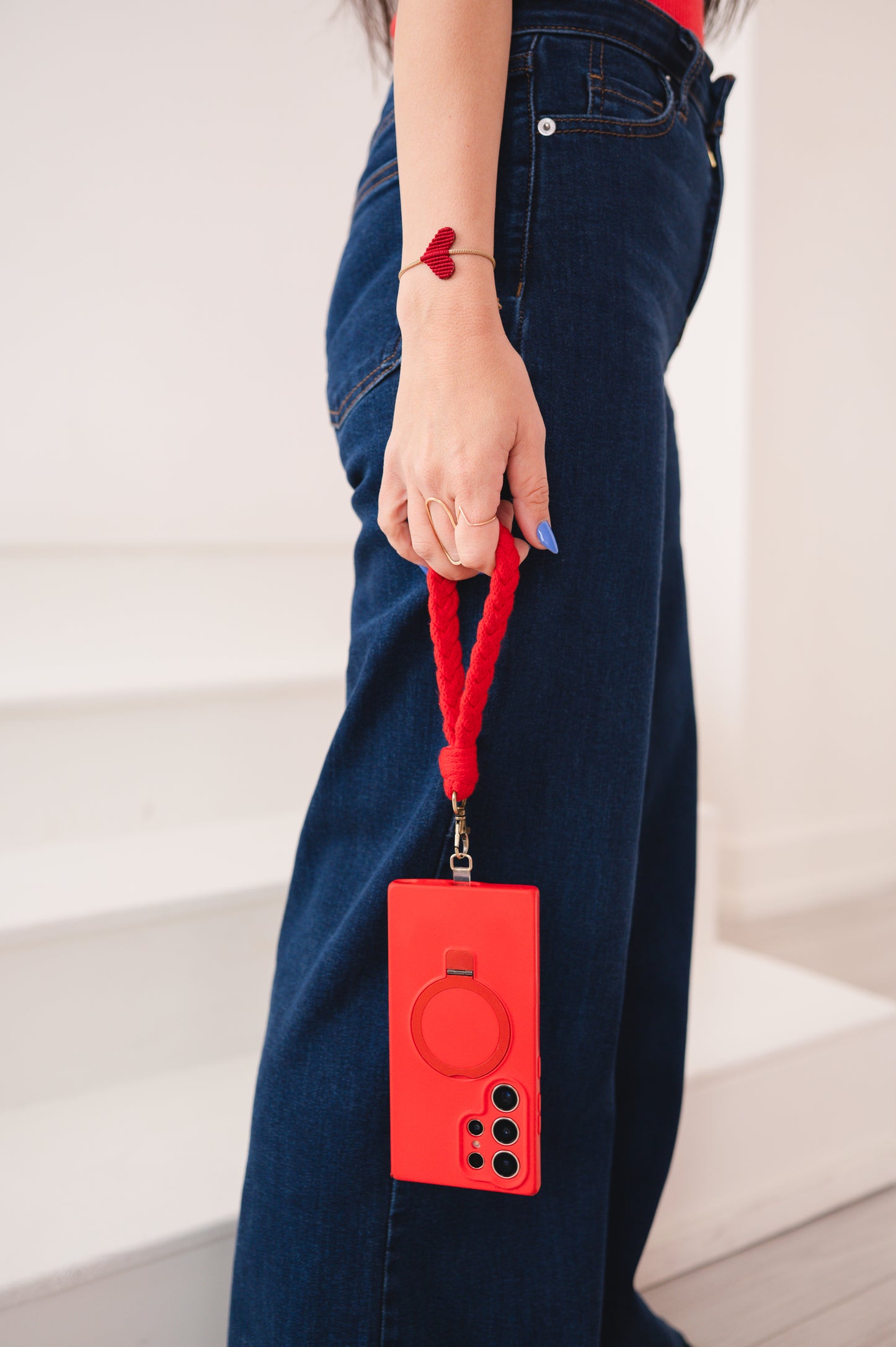 Person holding a red phone case with a lanyard against a white background